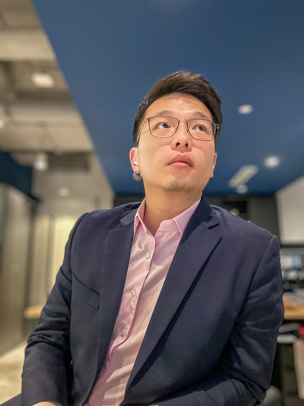 Ivor Ngo in a navy blazer and open collar in a modern Hong Kong office.